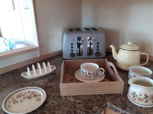 a kitchen counter with a coffee maker and cups and plates at Swifts Nest in Carnguwch