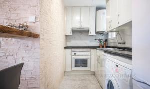 una cocina con armarios blancos y electrodomésticos blancos en TarracoHomes, TH134 Apartamento Llorer, en Tarragona
