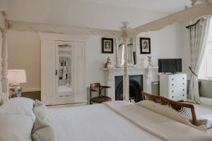a bedroom with a white bed and a fireplace at Allington Manor in Allington