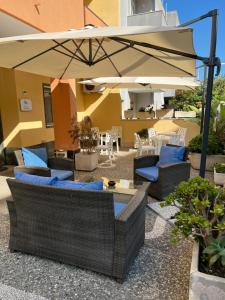 eine Außenterrasse mit Stühlen und einem Sonnenschirm in der Unterkunft Hotel Minerva in Otranto