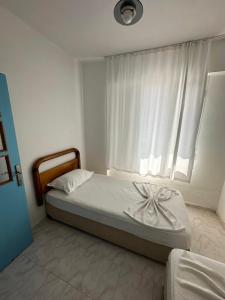 a bedroom with a bed and a window with white curtains at Beyaz Saray Apart Otel in Ayvalık