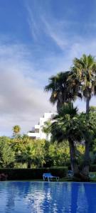 een zwembad met twee palmbomen en een gebouw bij Comfy 2BR, 2Bathroom, Parking, Pool, Sea Views, Elviria Alta in Ojén