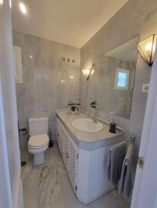 een badkamer met een wastafel, een toilet en een spiegel bij Comfy 2BR, 2Bathroom, Parking, Pool, Sea Views, Elviria Alta in Ojén