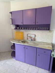 a kitchen with purple cabinets and a sink at Beyaz Saray Apart Otel in Ayvalık
