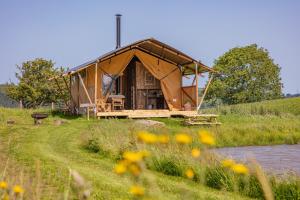 a large tent in a field next to a river at Under the Oak Glamping in Caerphilly