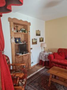 アウロンツォ・ディ・カドーレにあるChalet Elenaのリビングルーム(赤いソファ、テーブル付)