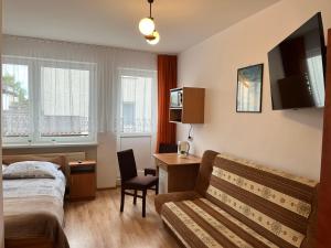 カルビアにあるPokoje Gościnne U RYBAKAのベッド、デスク、椅子が備わるホテルルームです。