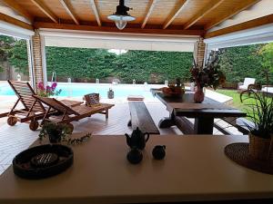 een woonkamer met een tafel en stoelen en een zwembad bij Celestial Azure Villa, your Athenian Country House Retreat in Markopoulon