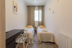 a room with two beds and a desk in it at Sagrada Familia Apartment in Barcelona