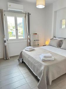 a white bedroom with a large bed with towels on it at Leo House Kea in Korissia