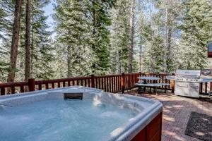 a hot tub on a patio with a grill and trees at Tahoe Discovery in South Lake Tahoe