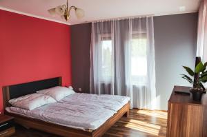 a bedroom with red walls and a bed in a room at Butik Apartmanház in Fonyód