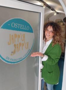 Eine Frau, die in einer Tür neben einem Schild steht. in der Unterkunft Japp'ca Japp'ca in Castellaneta