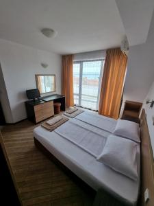 a large bed in a room with a large window at Стаи за гости Мистрал in Primorsko