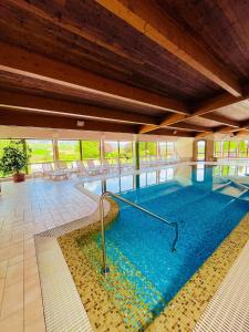 a large swimming pool with blue water in a building at Hétkúti Wellness Hotel in Mór