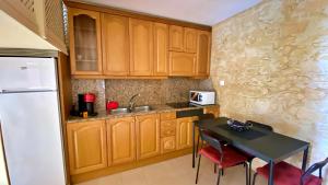 cocina con armarios de madera, mesa y nevera en Sonora Golf and rest apartment, en Santa Cristina d'Aro