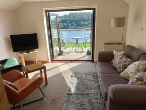 a living room with a couch and a tv and a balcony at Castle View Apartment in Dunvegan