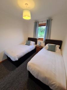 a bedroom with two beds and a window at Kings Reach - Crinan Cottage in Lochgilphead