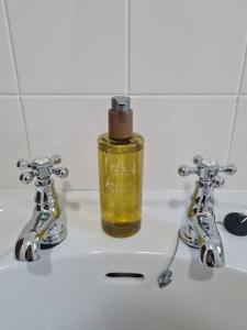 a bathroom sink with a bottle of oil between two faucets at Kings Reach - Crinan Cottage in Lochgilphead