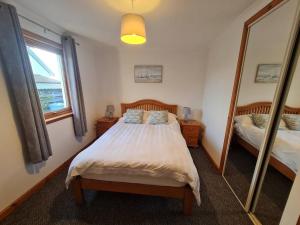 a bedroom with a bed and a large mirror at Kings Reach - Crinan Cottage in Lochgilphead