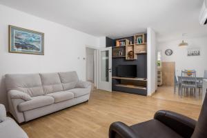 Una sala de estar con un sofá y un televisor. en Garden Home Flora, en Rijeka