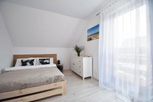 a white bedroom with a bed and a window at Domki Lilia Sarbinowo in Sarbinowo +37 photos
