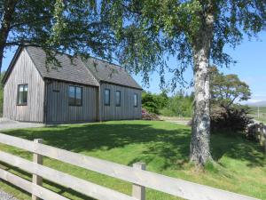 a barn with a white fence and a tree at Old Schoolhouse in Lairg