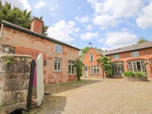 um velho edifício de tijolos com um portão em frente em Rectory Cottage em Oswestry