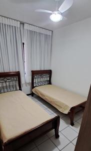 Duas camas num quarto com cortinas em Descanso a 100m do Mar em Itapema