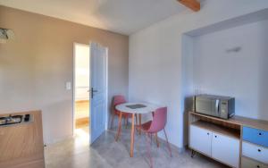 eine kleine Küche mit einem Tisch und zwei rosa Stühlen in der Unterkunft Bleu Azur - Trégor in Ploubezre