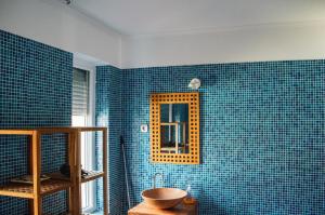 a blue tiled bathroom with a sink and a mirror at Butik Apartmanház in Fonyód +34 photos