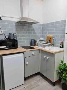 a kitchen with white cabinets and a sink and a microwave at Nice Flat near Central London in London