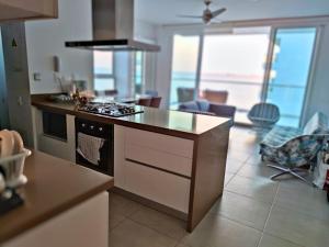 a kitchen with a stove top oven next to a living room at Playa Dormida 2. Hermoso apartamento frente al mar in Santa Marta