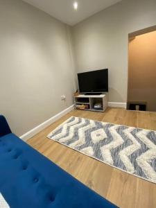 een woonkamer met een blauwe bank en een televisie bij Bowie's Abode in Sowerby Bridge