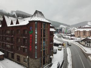 a building with a sign on it on a snowy street at Марина in Bukovel