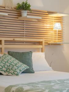 Una cama con almohadas verdes y blancas y una lámpara. en B&B La Villa 3.0, en Nonantola