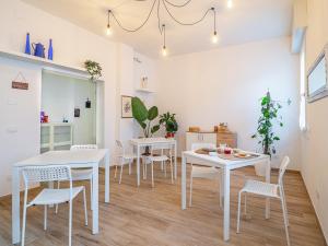 cocina y comedor con mesas y sillas blancas en B&B La Villa 3.0, en Nonantola