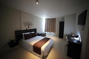 Habitación de hotel con cama, escritorio y ventana en Suche Park Hotel, en Piura