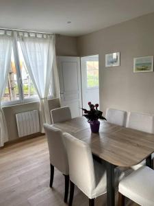 een eettafel met witte stoelen en een vaas met bloemen bij Maison de charme proche centre-ville in Dieppe