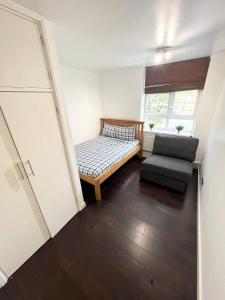 een kleine kamer met een bed en een stoel bij Large apt close to central LDN in Londen