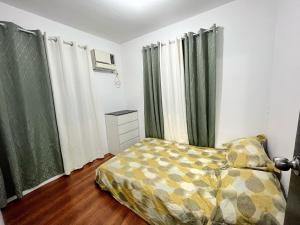 1 dormitorio con cama y cortinas verdes en Montierra Subdivision Staycation CDO en Cagayán de Oro