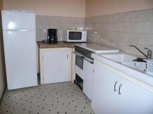 uma cozinha com um frigorífico branco e um micro-ondas em Le moulin em Préchacq
