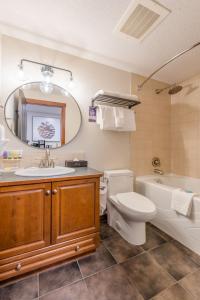 a bathroom with a sink toilet and a tub and a mirror at Blackstone Mountain Lodge by CLIQUE in Canmore