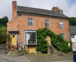 een rood bakstenen huis met gele deuren en klimop bij The Old Stores in Montgomery
