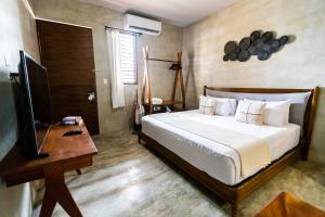 a bedroom with a bed and a desk and a television at Hotel Siesta Holbox in Holbox Island