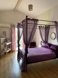 a bedroom with a canopy bed with purple sheets at Villa Monplaisir Zen in Latrape