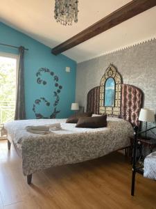 a bedroom with a large bed and a blue wall at Villa Monplaisir Zen in Latrape