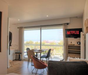 sala de estar con mesa y sillas y balcón en Trésor d'Opale T1 VUE MER BALNÉO-SPA PARKING PRIVÉ WIFI NETFLIX 3 PERS, en Berck-sur-Mer