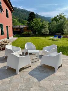 - un ensemble de chaises et de tables blanches sur une terrasse dans l'établissement MARCO APARTMENTS di Locanda da Marco, à Pignone