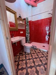 y baño con aseo, lavabo y azulejos rojos. en Apartamentos la Selva - Rafael de la Viesca, en Cádiz